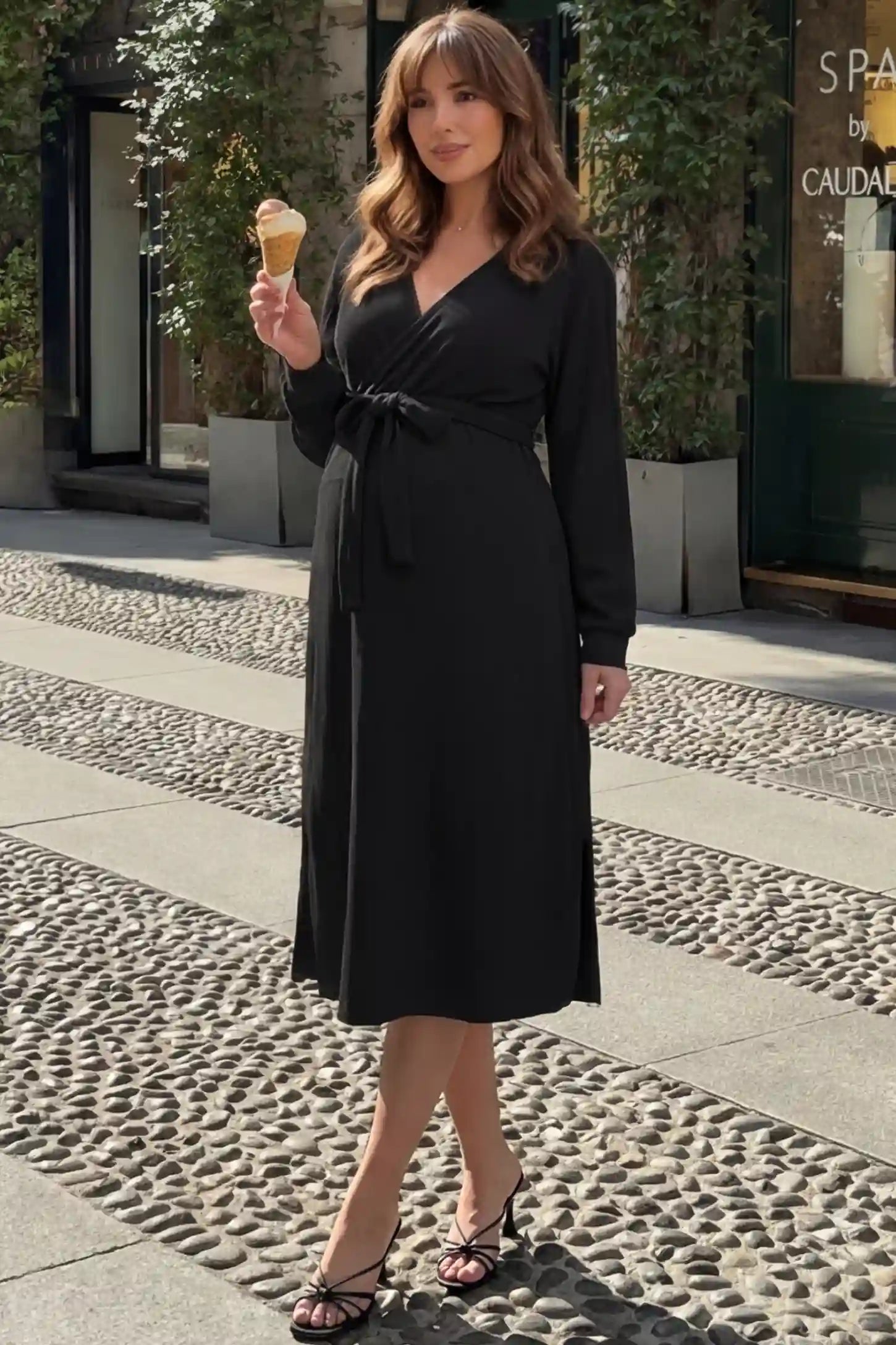 Wrap Front Tie Waist Long Sleeve Maternity Midi Dress Wrap Front Tie Waist Long Sleeve Maternity Midi Dress in Black featuring adjustable tie waist and side slits on a pregnant woman in outdoor setting, front view.