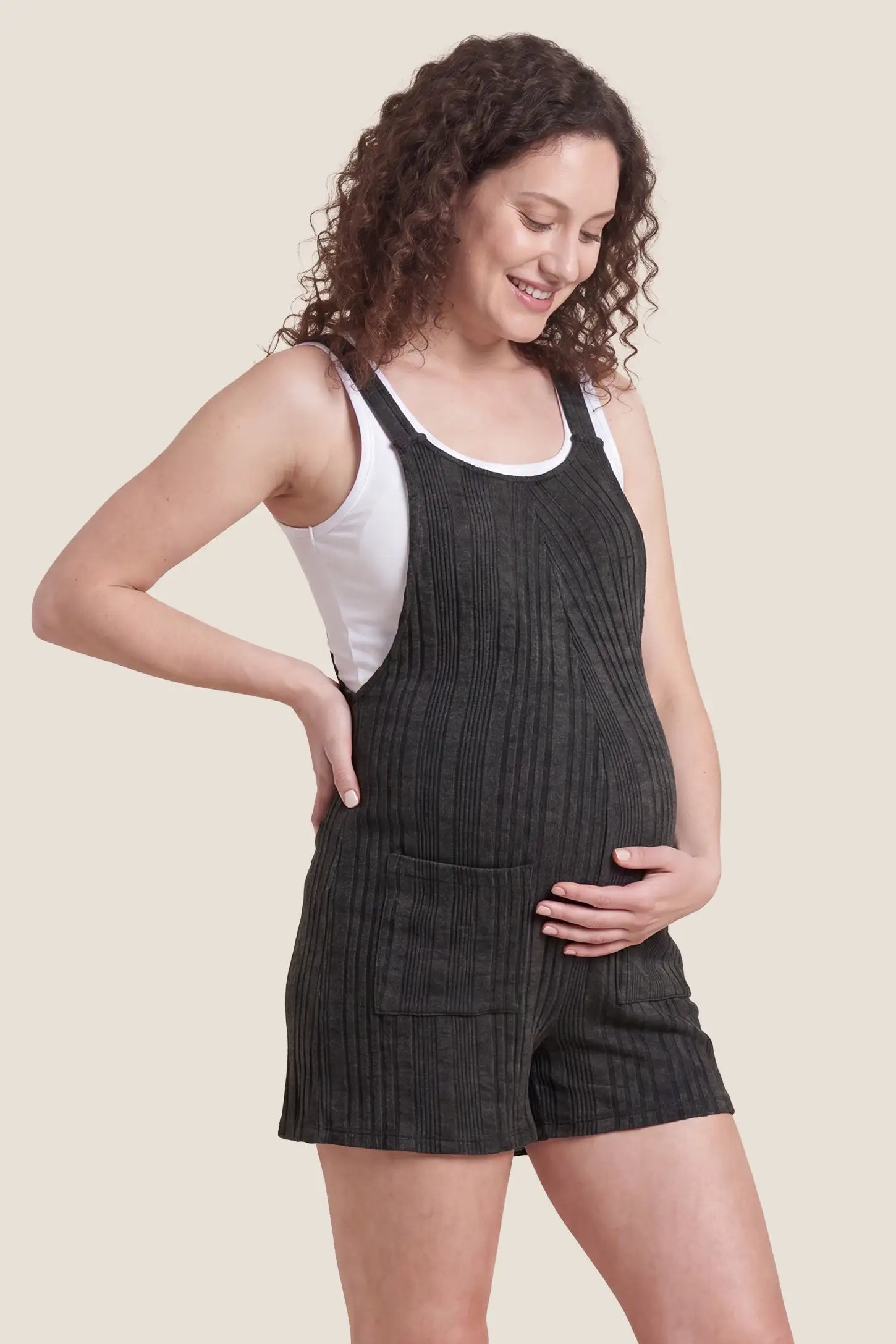Ribbed Pocket Knit Maternity Romper Ribbed Pocket Knit Romper in Black featuring a flexible ribbed knit fabric on a pregnant model, side view.

