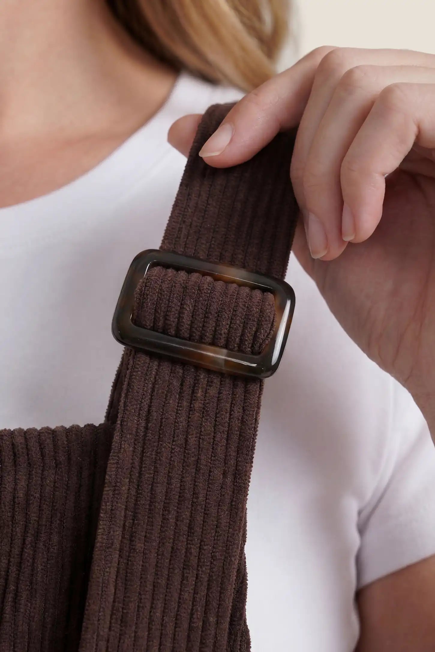 Close-up detail of adjustable strap on brown wide leg side stretch panel maternity overalls